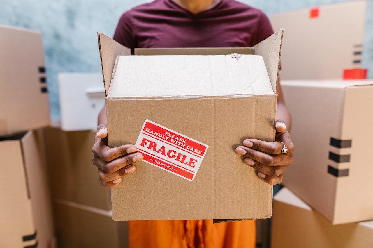 Person holding a moving box with a frangile sticker